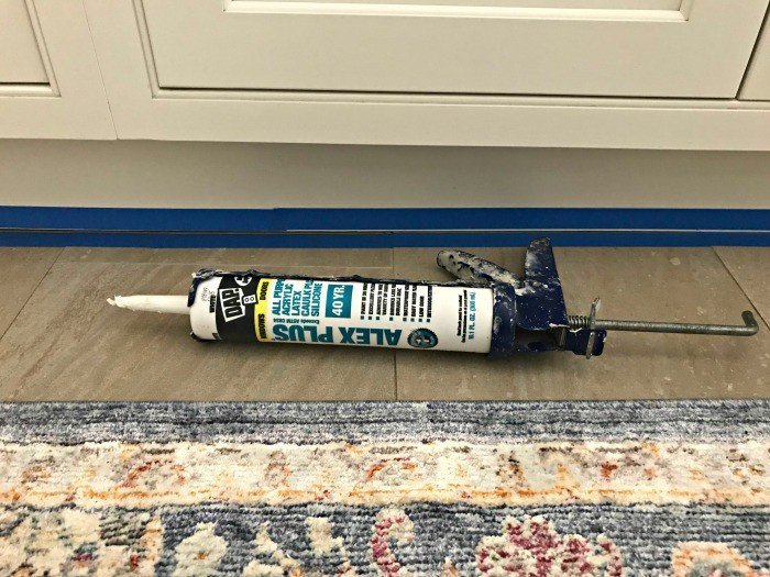 Fix that small gap under cabinets in your kitchen, bath, and laundry with this quick and easy DIY update. For less than $10 and in 30 minutes you can caulk that gap and block out all of the spills, dirt, and crumbs that get caught in the crack.
