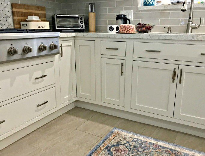 Caulking that small gap between cabinets and floor tile is an easy way to make your kitchen look nicer. And it stops all of those crumbs and spills from hiding under those cabinets. YASSS!