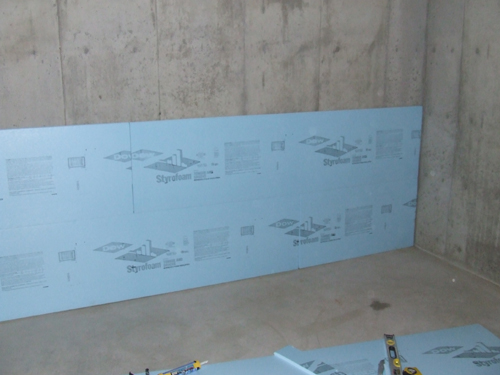 Picture of XPS Blue Board Being Installed on the inside of a foundation wall